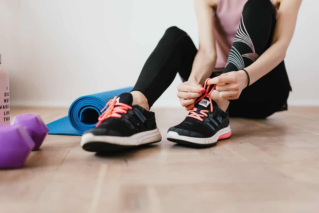 A woman putting her sneakers on for a cross-training workout