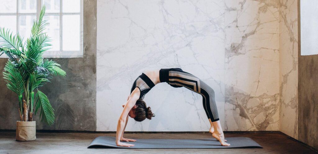 A female performing a back wheel stretch at a gym on a Pilates mat