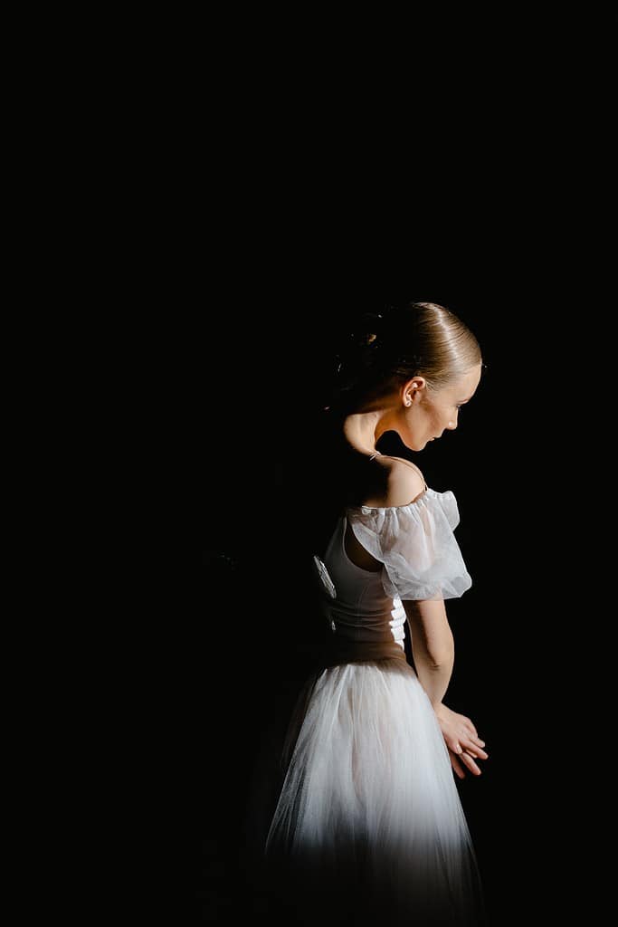 A ballerina dress in white staring off into the distance during a ballet audition