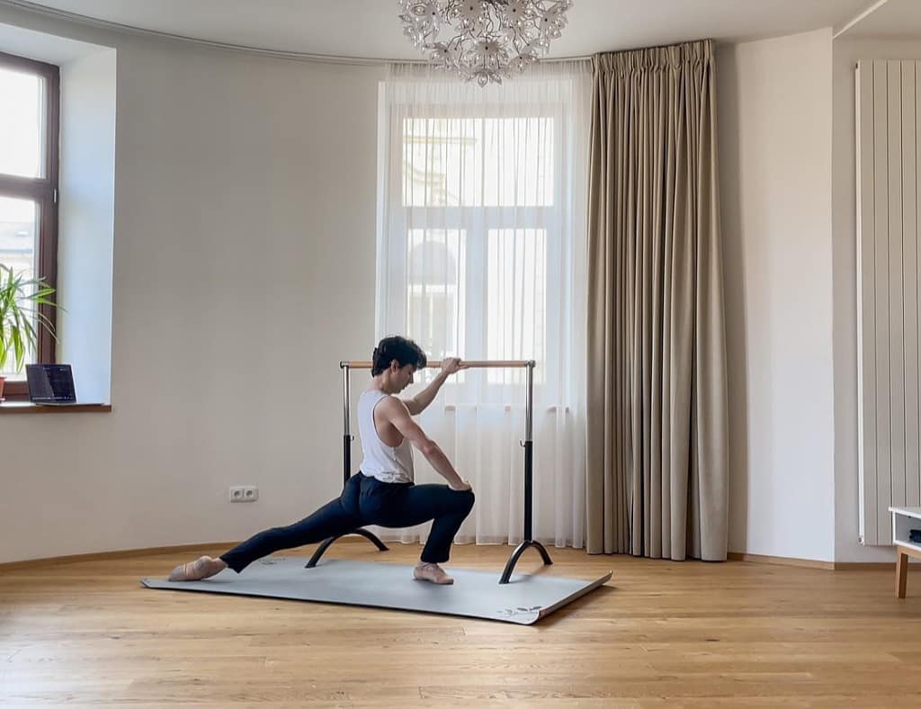 a male dancer in a large home dance studio with potrable flooring and ballet barre