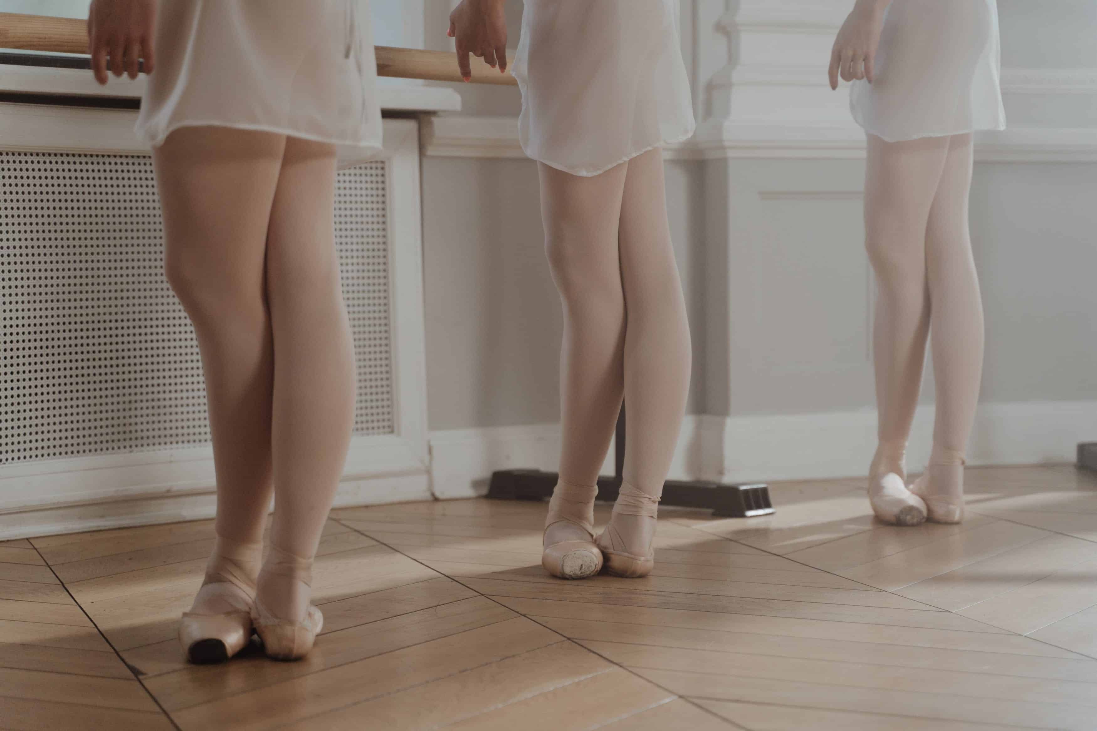 Three dancers standing at the barre in fifth position