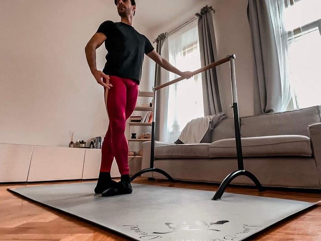 Male dancer in his own dance studio containing portable flooring and ballet barre