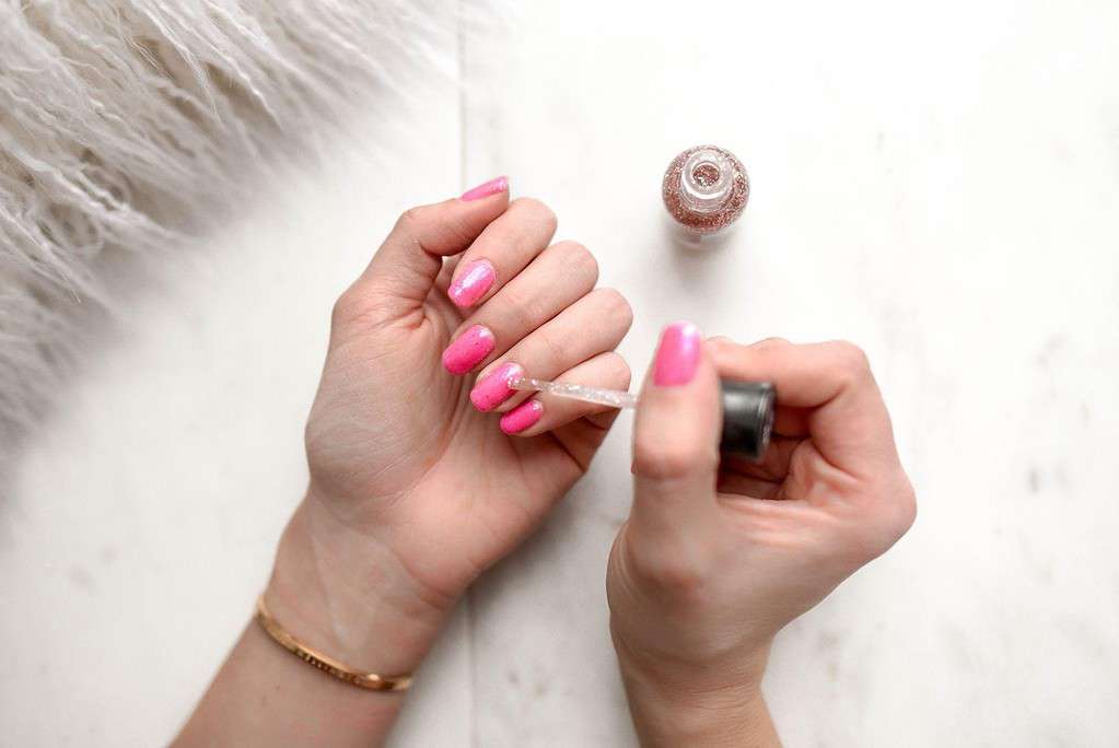 A female applying pink nail polish