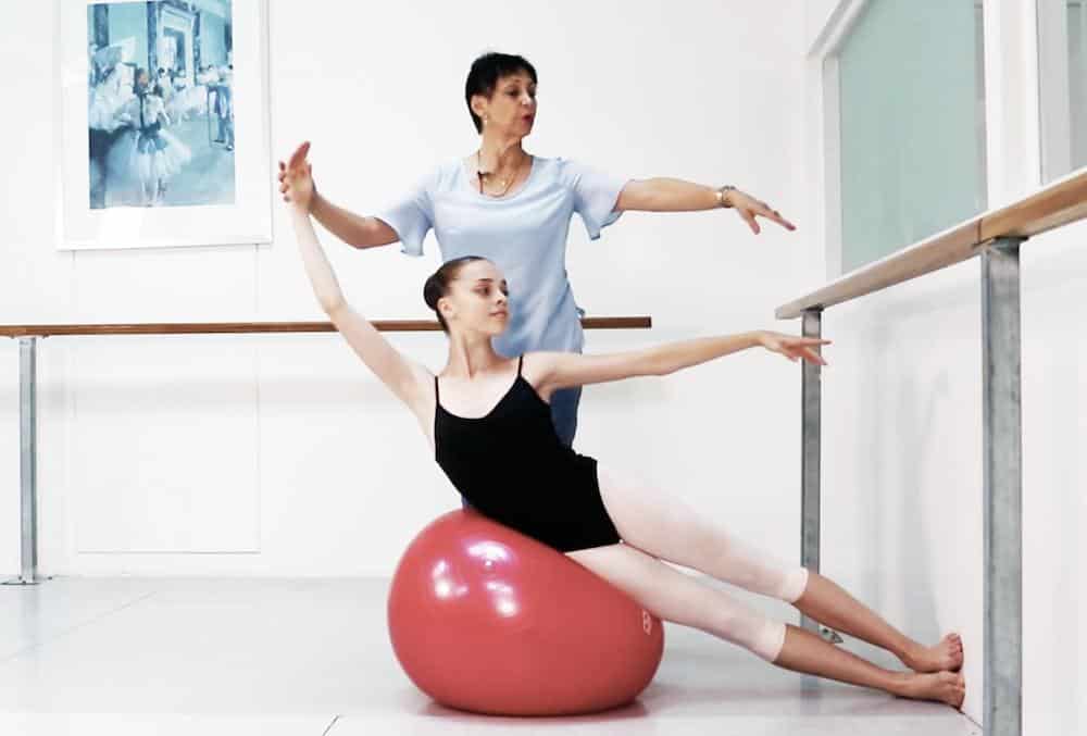 Teacher and student performing Progressive Ballet Technique exercise on medicine ball