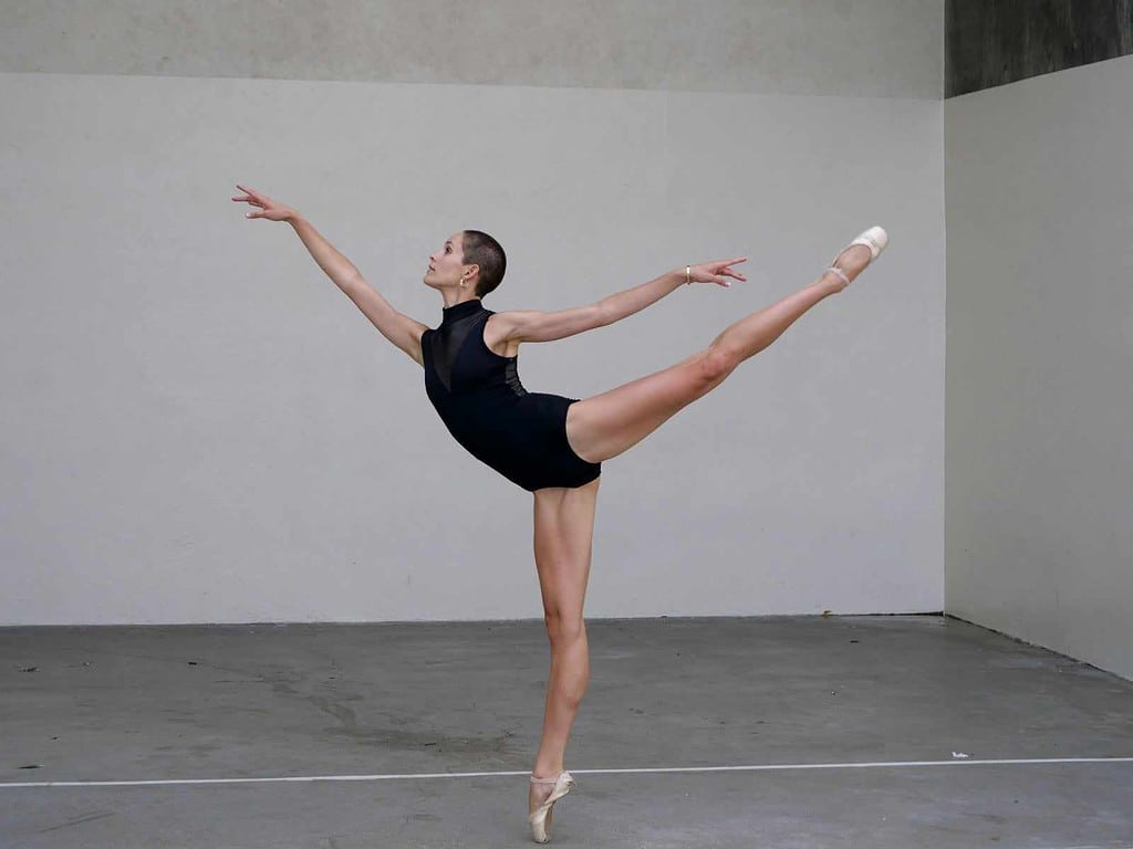 Female ballerina performing ballet arabesque in dance studio