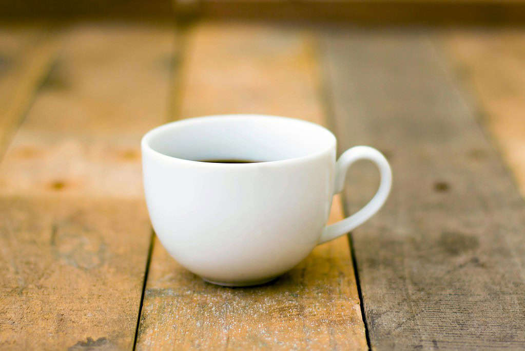 White teacup against wooden benchtop