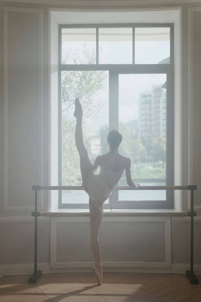 Female dancer using a double ballet barre in home studio