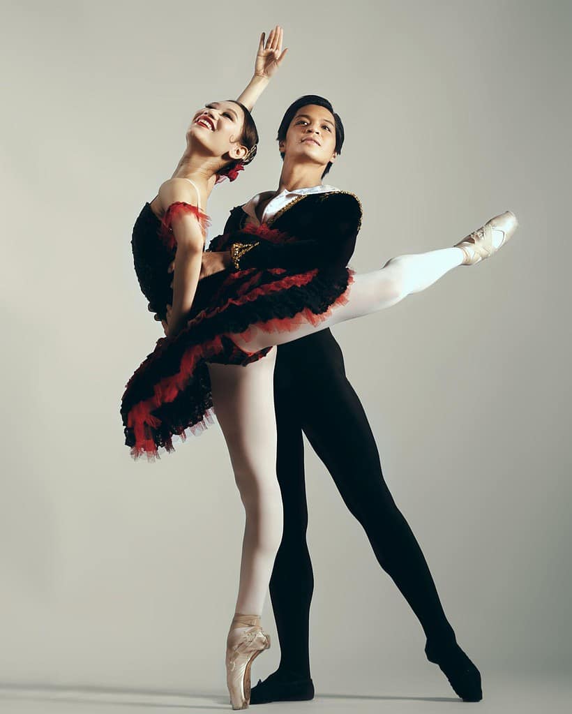 Abigail Oliveiro with partner performing arabesque in red and black tutu