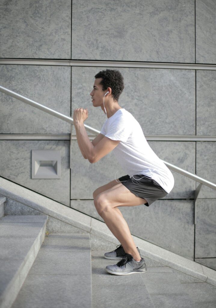 Male performing squats on an outdoor staircase