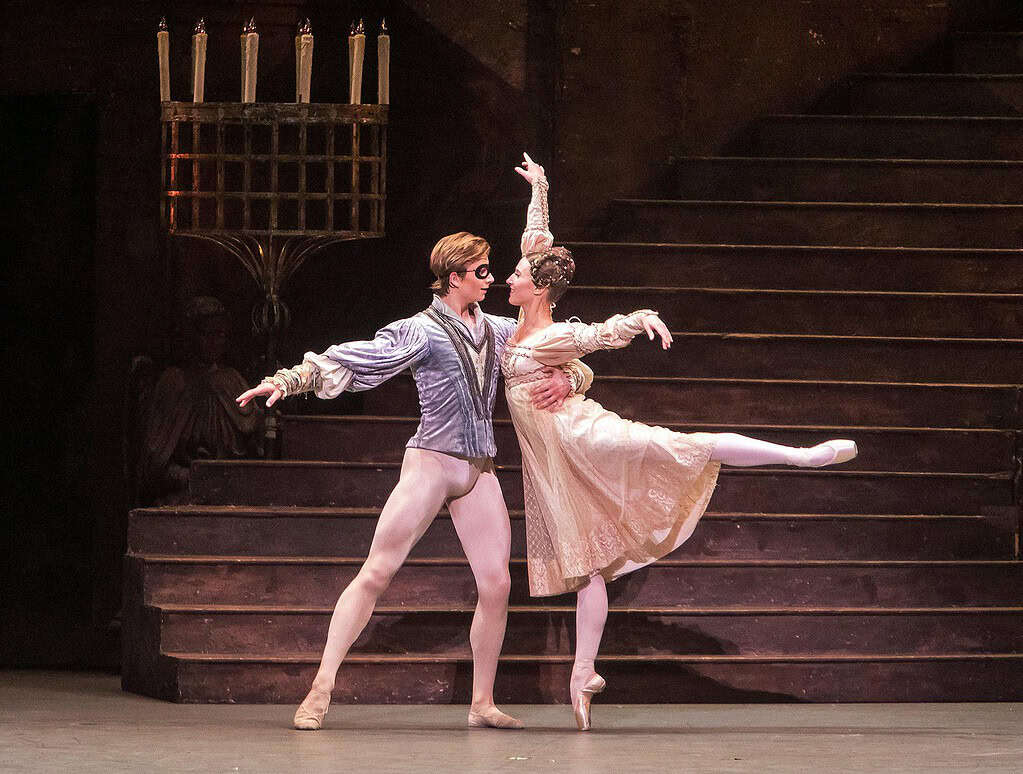 Romeo and Juliet wearing masks at the Capulet ball during ballet performance on stage