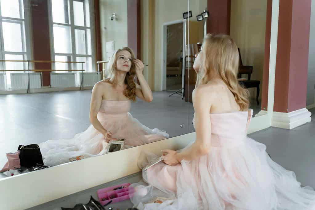 Ballerina applying makeup in dance studio