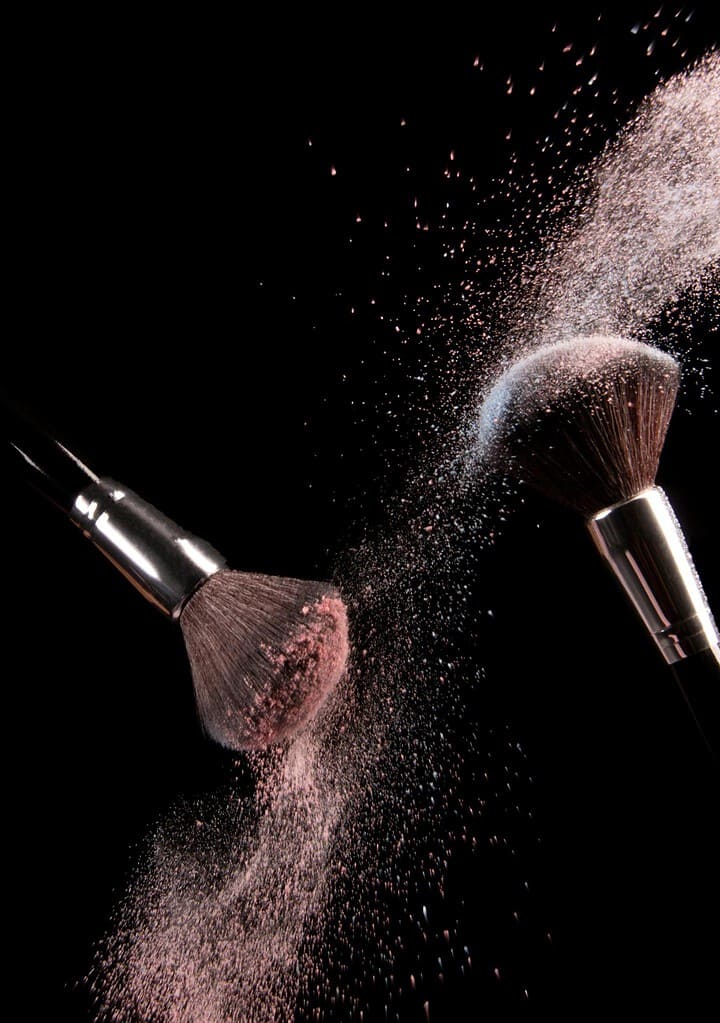 Two makeup brushes applying blush