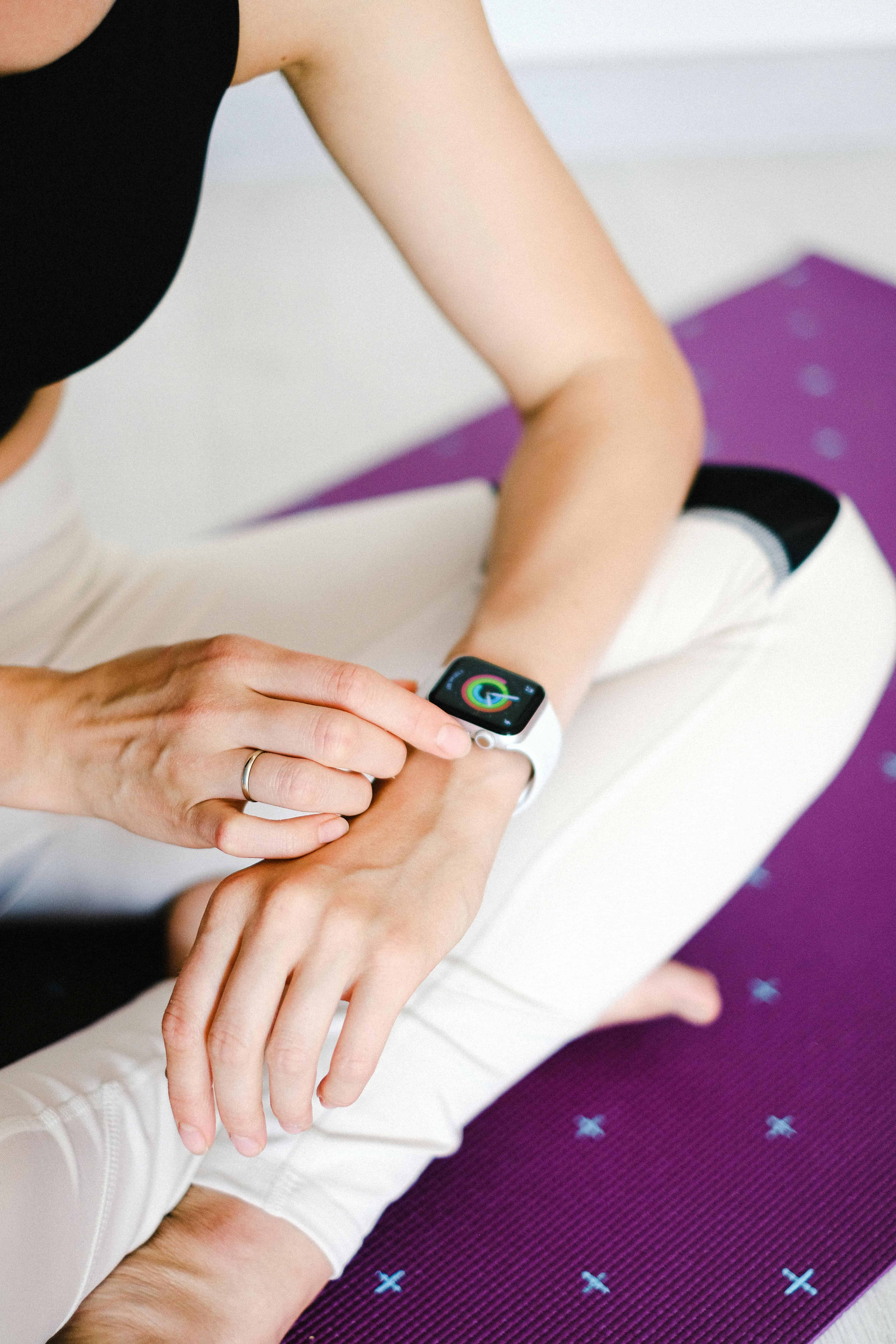 Female dancer wearing a smart watch while sitting on Pilates mat