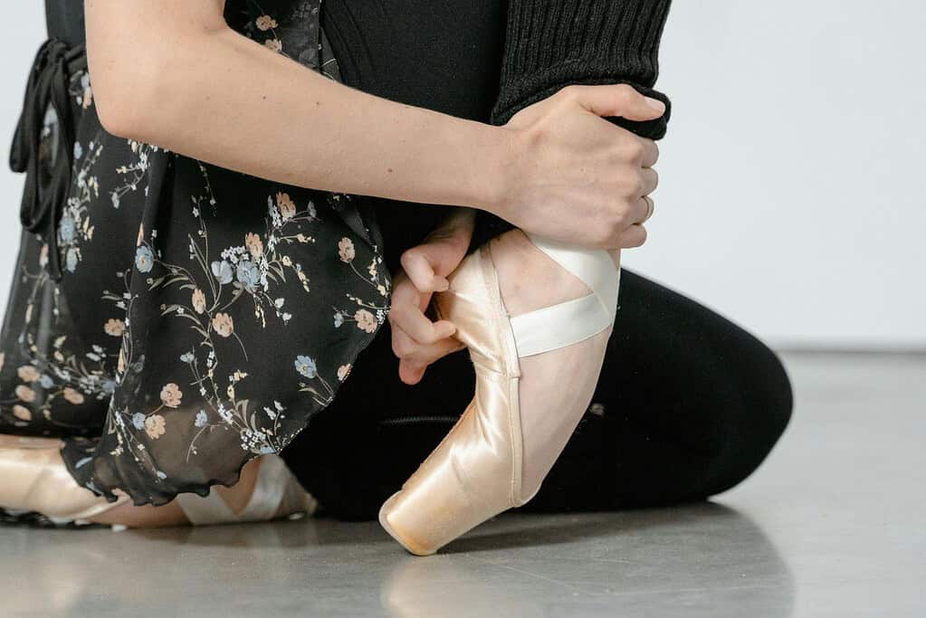 Dancer gently stretching to break in pointe shoes