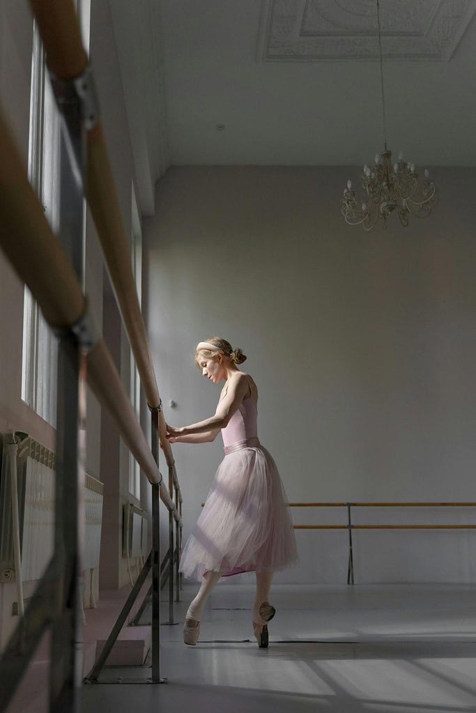 Dancer wearing pointe shoes at the barre to break in shoes