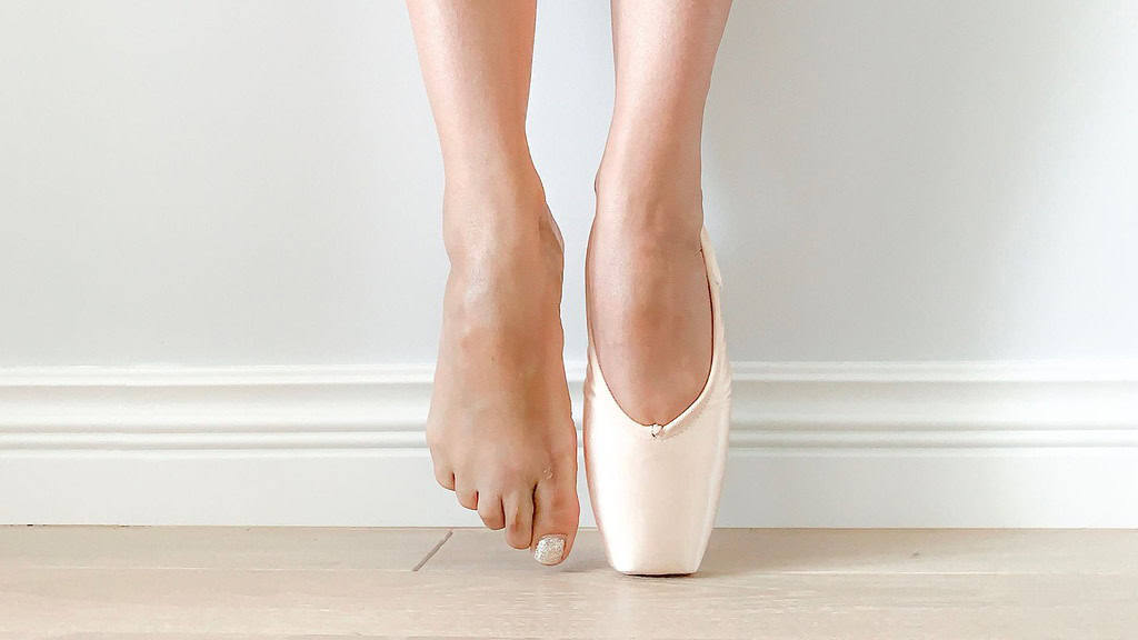 Female dancer en pointe with one foot in a pointe shoe