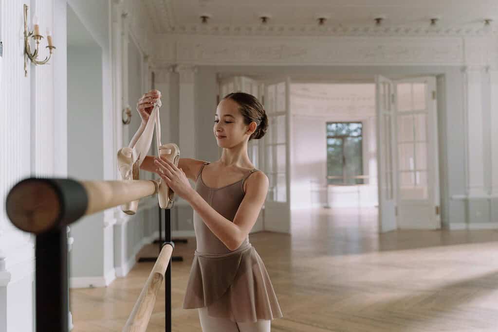 Young aspiring dancer holding up a pair of pointe shoes