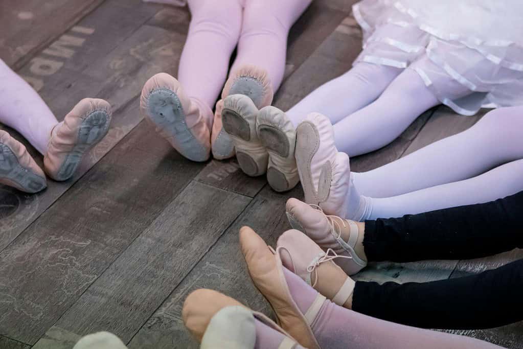 Young dancers in a circle showing off their ballet flats