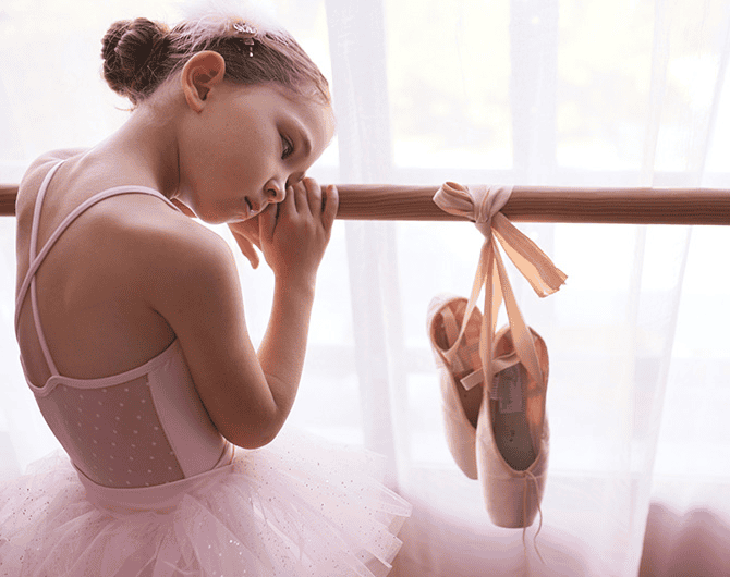 Young girl dreaming of wearing pointe shoes