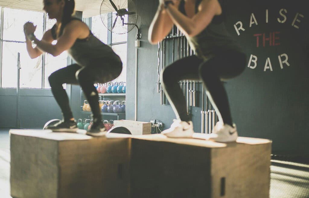 Two women doing box jump at gym