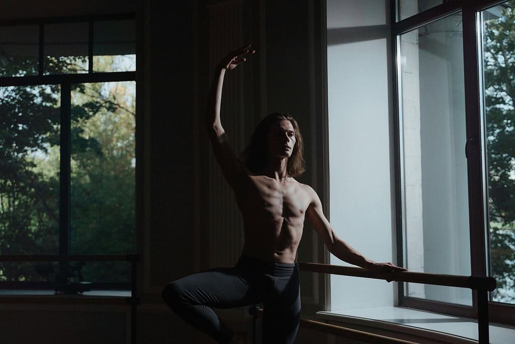 Male dancer practising ballet turnout at the barre