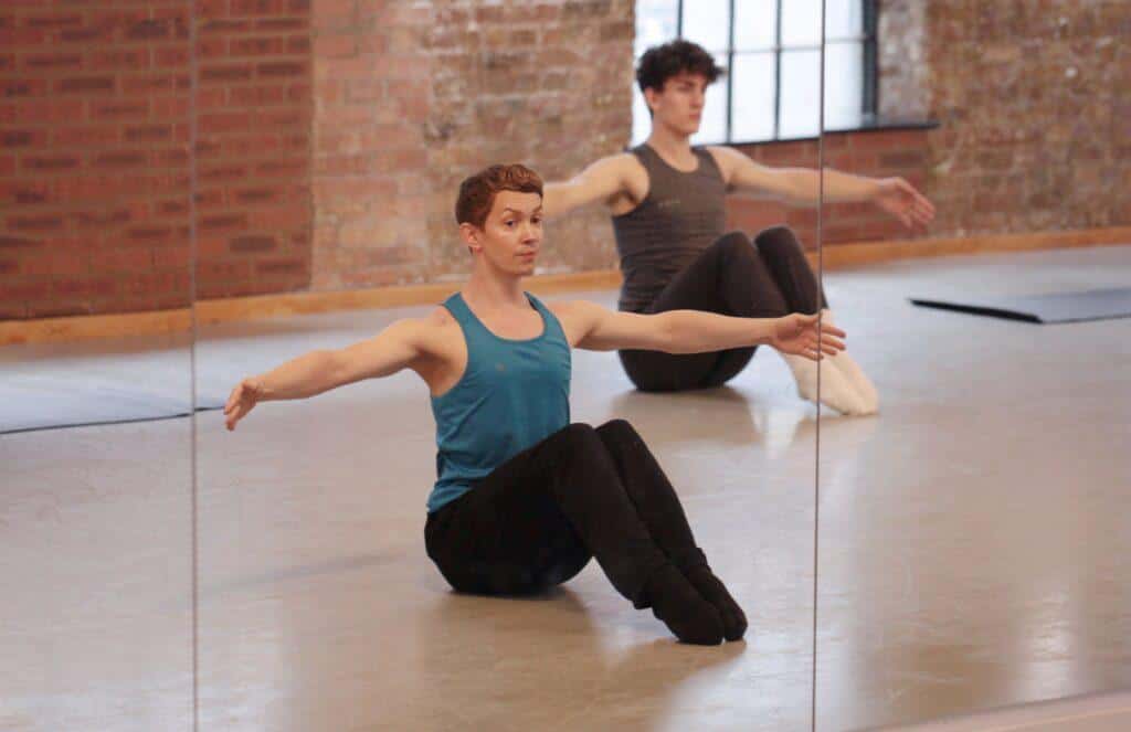 Two male dancers performing ballet floor barre in dance studio